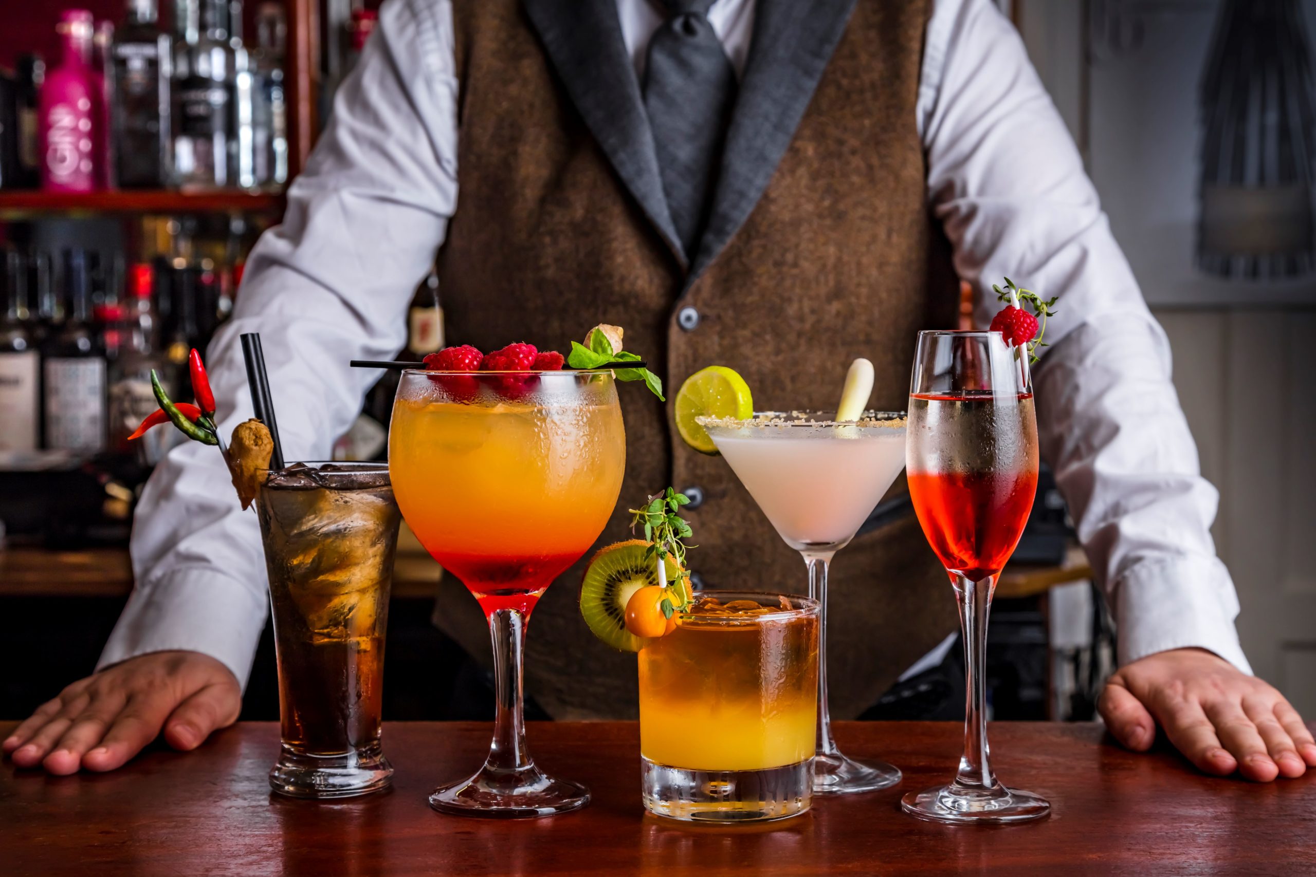 Bartender stood behind five cocktails at a bar