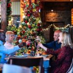 Four people saying cheers surrounded by Christmas decorations