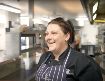 A smiling chef in a pub kitchen