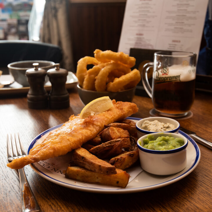 A plate of fish and chips with a pint of beer