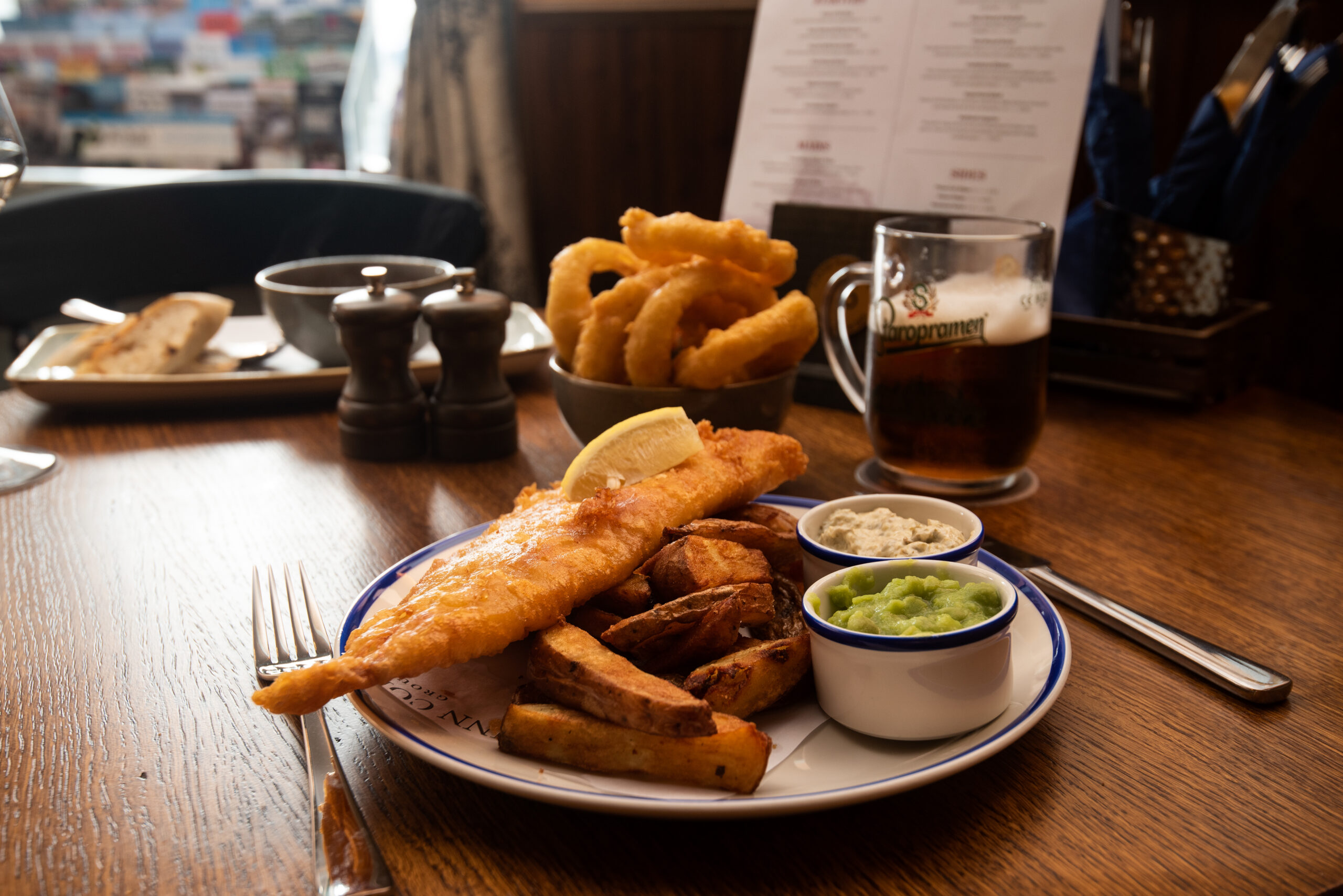A plate of fish and chips with a pint of beer
